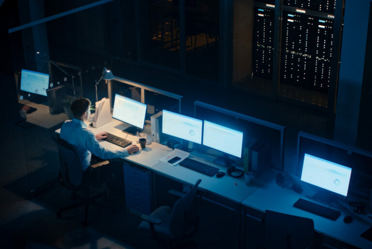 Working Late at Night in the Office: Businessman Using Desktop Computer, Analyzing, Using Documents, Solving Problems, Finishing Project. High Angle Shot